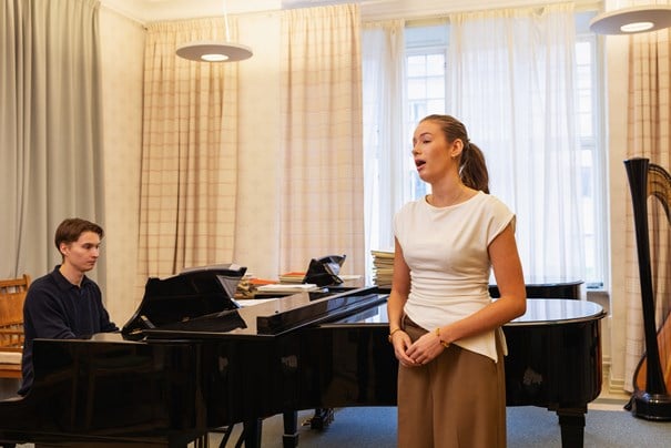Kille vid piano och tjej som sjunger.